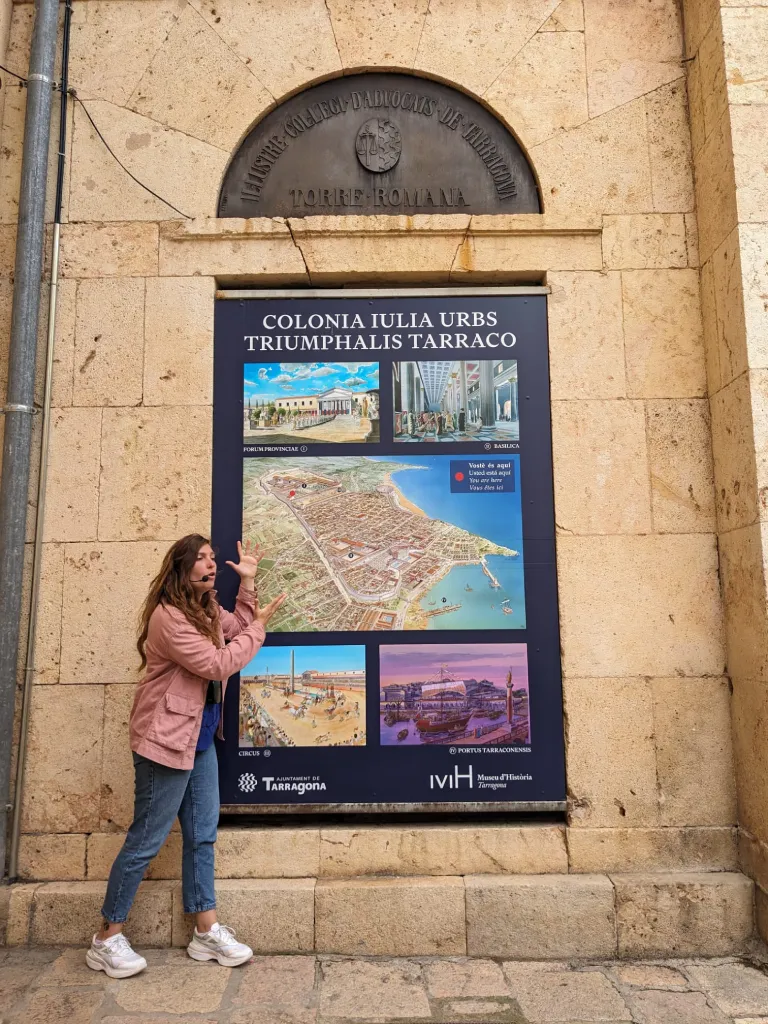 Tour guide standing in front of a map of the ancient Tarraco, with the title: 'Colonia Iulia Urbs Triumphalis Tarraco' in Tarragona.
